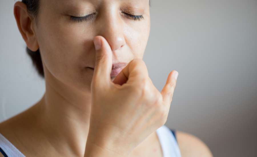 Pratique de respiration alternée (Nadi Shodhana) : femme fermant une narine avec les doigts pour apaiser le mental et améliorer la concentration.